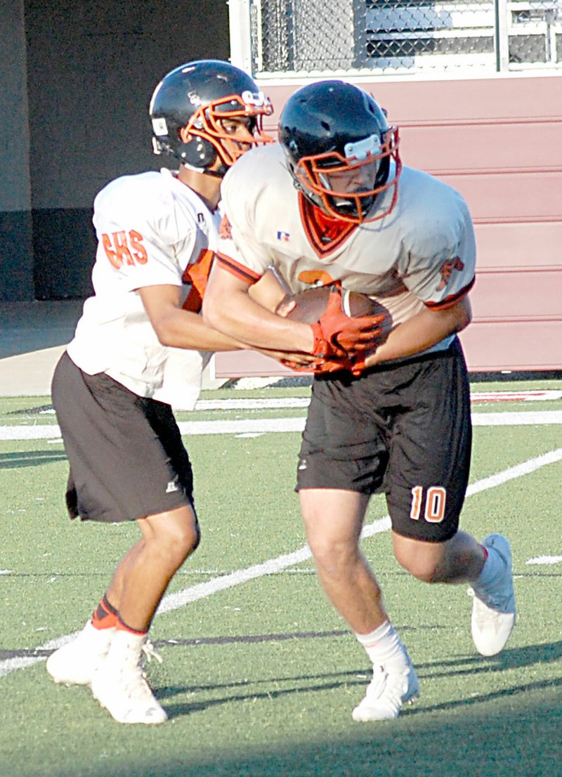 Photo by Graham Thomas Gravette quarterback Tajae White hands off to Austin O&#8217;Brien at Thursday&#8217;s team camp in Siloam Springs.