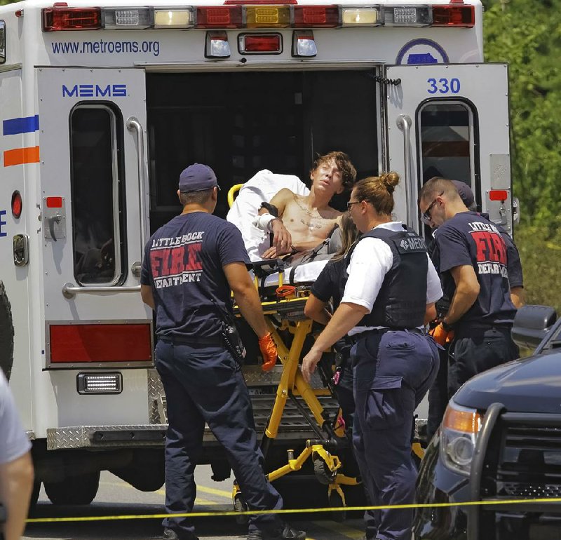 Emergency personnel load a man into an ambulance at the scene of a shooting by a police officer on West Markham Street in west Little Rock on Wednesday afternoon.