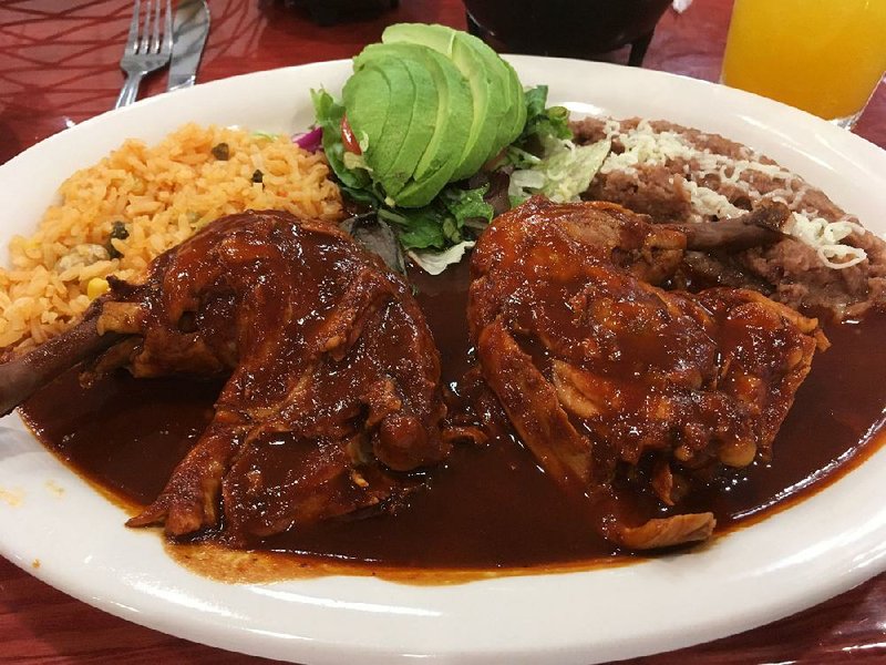 Pollo With Mole Poblano — two leg quarters in a thin but flavorful mole — comes with rice, beans and a sliced fresh avocado at La Hacienda. 