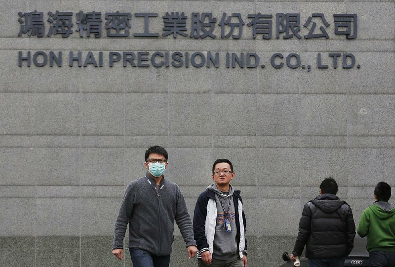 Employees enter and exit the headquarters of Taiwan’s Hon Hai Precision Industry Co., also known as Foxconn, in New Taipei City, Taiwan, in this 2016 fi le photo. Wisconsin is close to persuading iPhone manufacturer Foxconn to build a large manufacturing plant in the state, two state lawmakers said Thursday.