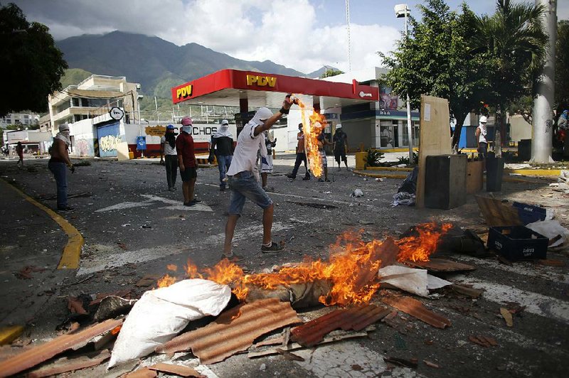 An anti-government demonstrator lights a fire at a roadblock Thursday in Caracas, Venezuela. 