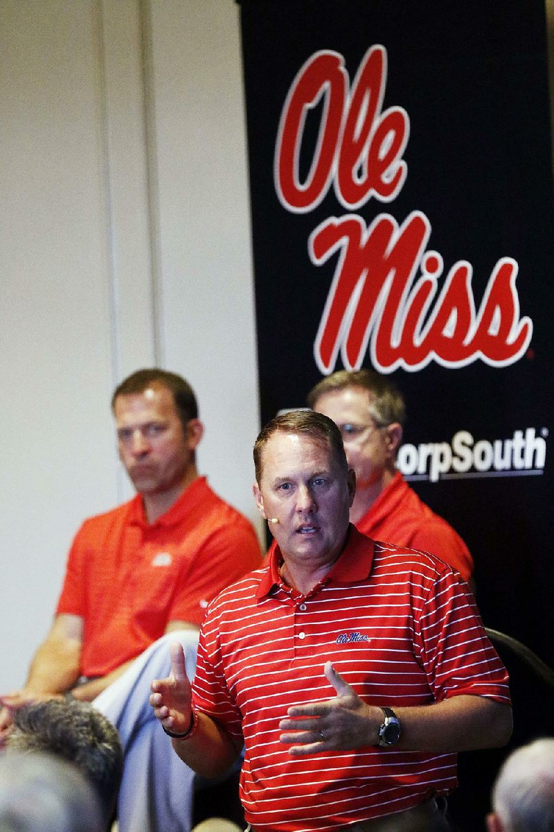 In this Tuesday, July 18, 2017, photo, Mississippi athletic director Ross Bjork, left, and Mississippi Chancellor Jeffrey Vitter, partially obscured, listen as football coach Hugh Freeze speaks before alumni and athletic supporters during a Rebel Road Trip visit in Jackson, Miss. Mississippi announced Thursday that Freeze had resigned after five seasons, bringing a stunning end to a once-promising tenure. Offensive line coach Matt Luke has been named the interim coach. 