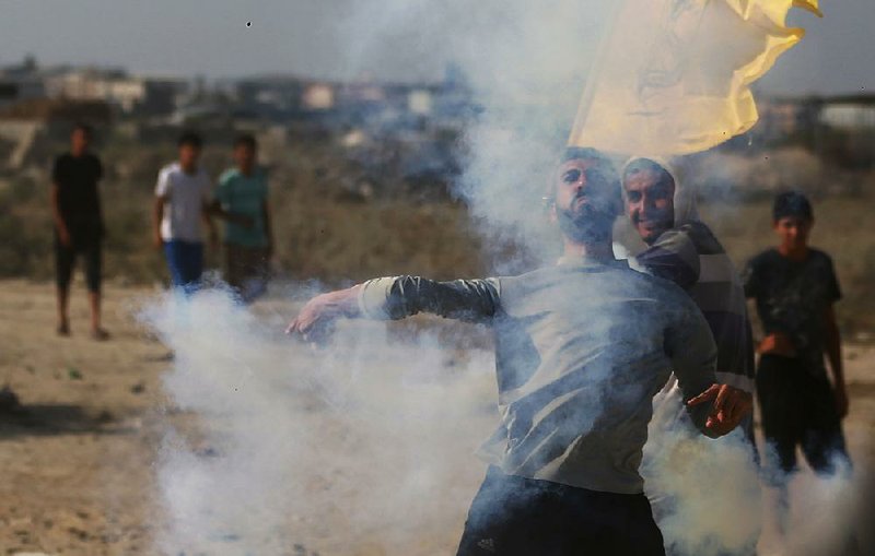 A Palestinian protester on Friday throws back a tear gas canister fired by Israeli soldiers during clashes on the Israeli border with Gaza related to protests against metal detectors Israel installed at a shrine in Jerusalem.