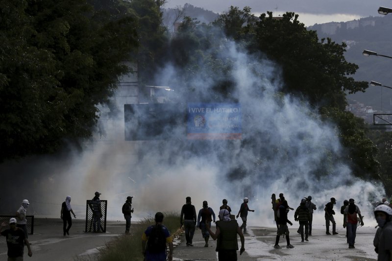 Demonstrators walk amid tear gas fired by Bolivarian National Guards during clashes in the El Hatillo neighborhood on the outskirts of Caracas, Venezuela, Thursday, July 20, 2017. Venezuelan President Nicolas Maduro and his opponents face a crucial showdown Thursday as the country's opposition calls a 24-hour national strike. 
