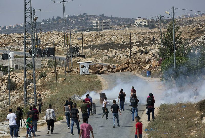 Palestinians clash with Israeli soldiers Saturday in the West Bank village of Kobar as an army bulldozer closes the road during an operation to search and measure for demolition the family home of Omar al-Abed, identified by the Israeli army as the assailant in a Friday attack at an Israeli settlement.