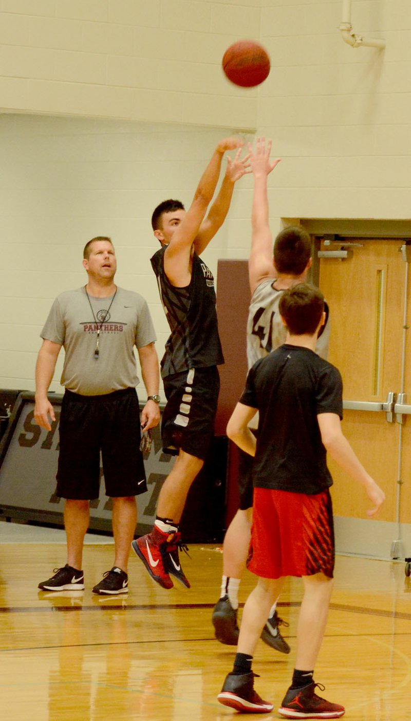 Graham Thomas/Siloam Sunday Junior guard Karson Clement shoots a 3-pointer over the outstretched hand of sophomore Jordan Stewart as head coach Tim Stewart looks on during Thursday&#8217;s practice inside the Panther Den.