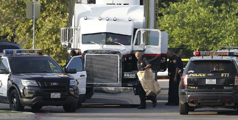 San Antonio police officers investigate the scene where people were found dead on Sunday in a tractor-trailer outside a Wal-Mart store in stifling summer heat.