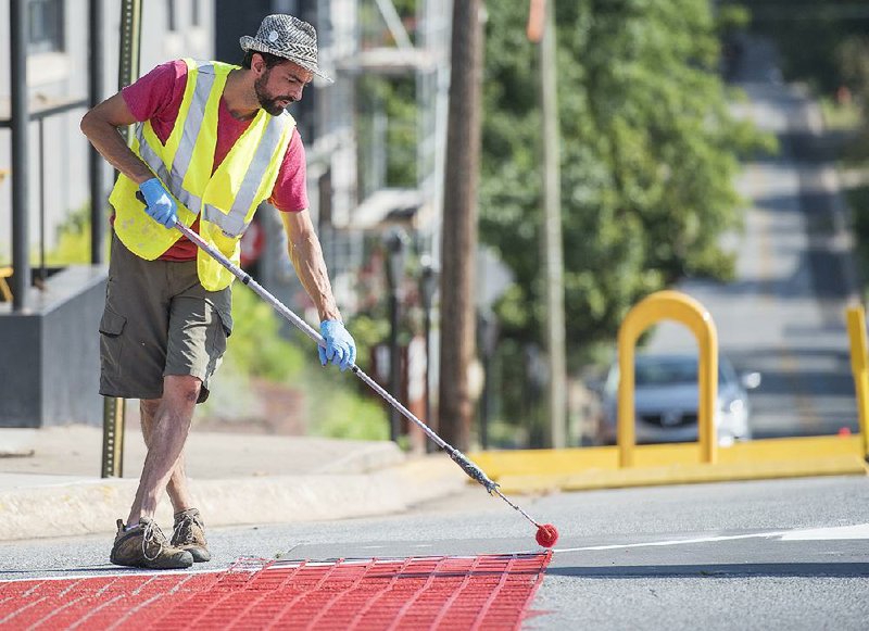 Michael Ward of Fayetteville works Sunday painting new crosswalk and curb extensions at Church Avenue and West Center Street as part of Fayetteville’s new tactical urbanism program.