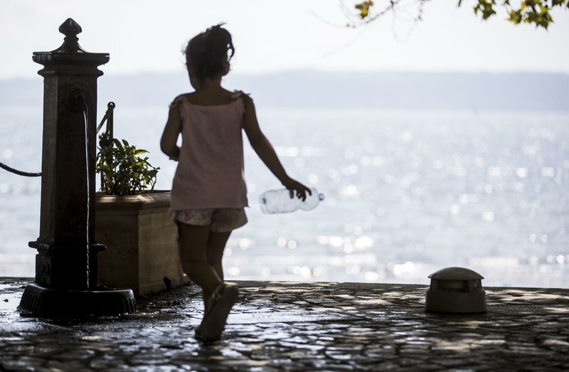 A little girl approaches a drinking water fountain to fill a bottle with water next to Lake Bracciano, about 35 kilometers northwest of Rome, Italy, Saturday, July 22, 2017. The lake's level has fallen sharply due to the drought and because a local water company has been taking more water from it than usual to meet demand. Italy is gripped by drought as the summer heat continues with no sign of rain. (Massimo Percossi/ANSA via AP)