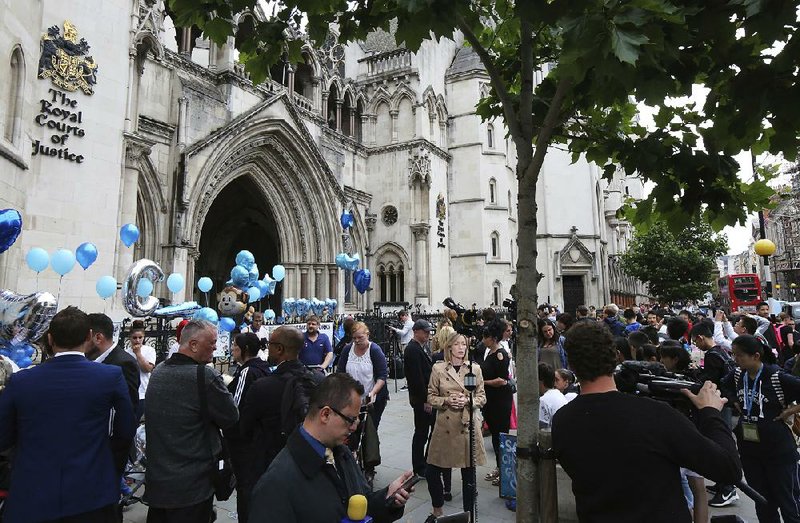 Supporters of critically ill baby Charlie Gard wait outside the High Court in London after his parents Connie Yates and Chris Gard spoke Monday.