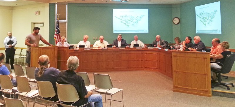 NWA Towing and Recovery owner Peyton Hillis (left) speaks Tuesday to Springdale's City Council before the vote allowing the Police Department choosing NWA Towing as the department's exclusive wrecking service.