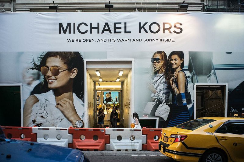 Customers exit a Michael Kors store under construction in New York on June 11. The handbag- maker has agreed to buy Jimmy Choo PLC for about $1.2 billion. 
