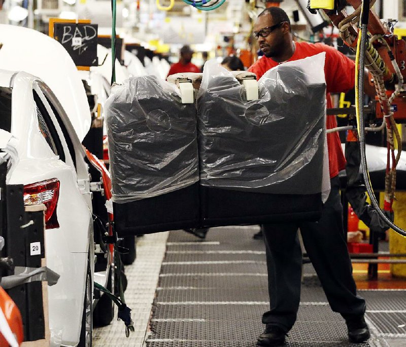 An assembly line worker uses a lift to move a back seat into a new Nissan Altima sedan at the Nissan Canton Vehicle Assembly Plant in Canton, Miss. 