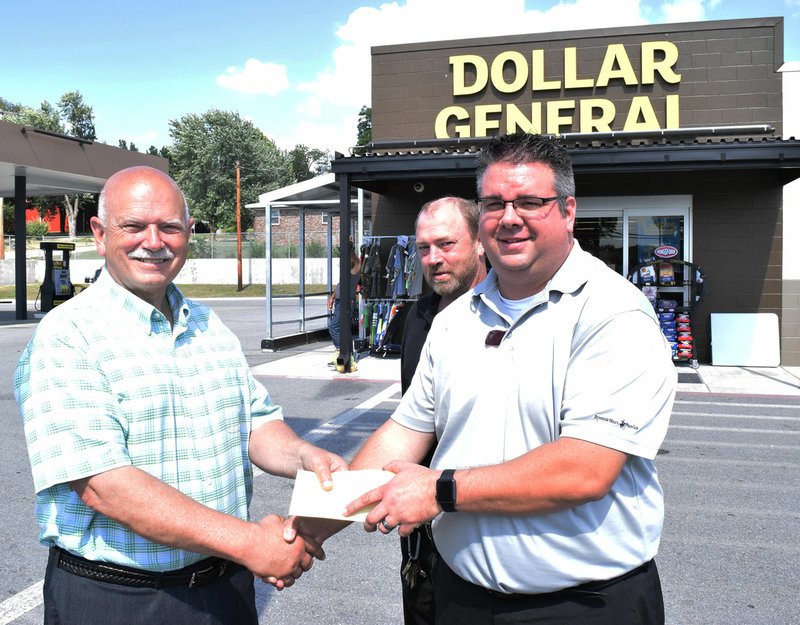 Photo by Mike Eckels Mayor Bob Tharp (left) received a gift of $1,000 from Matt Cooper, Dollar General regional manager, and Scott Frazier (back row), store manager, outside the Dollar General Plus-Plus store on Main St. in Decatur July 21. Dollar General&#8217;s donation will go towards the purchase of goals for the Veterans Park Soccer Complex.