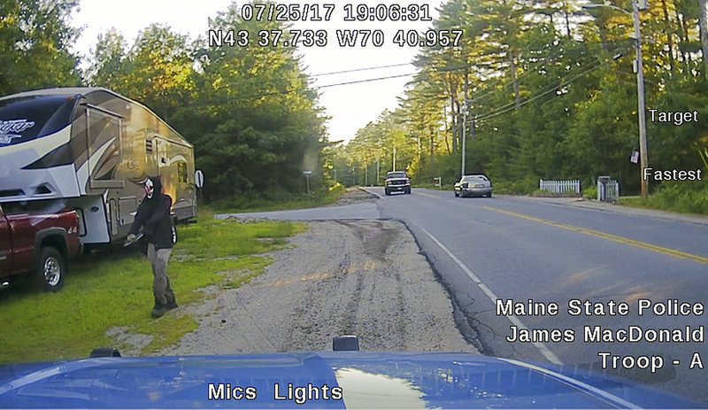 This Tuesday, July 25, 2017, patrol car dashboard-camera image released by the Maine State Police shows a man strolling down a street in Hollis, Maine, The police said he was wearing a clown mask and had a machete taped to his amputated arm.