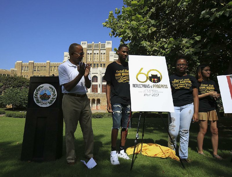 City Manager Bruce Moore (from left) applauds Wednesday as Little Rock Central High School students Tarvoais Carroll, 18, and Breyona Butler, 17, unveil the logo for this year’s commemoration of the 60th anniversary of the integration of the school. 
