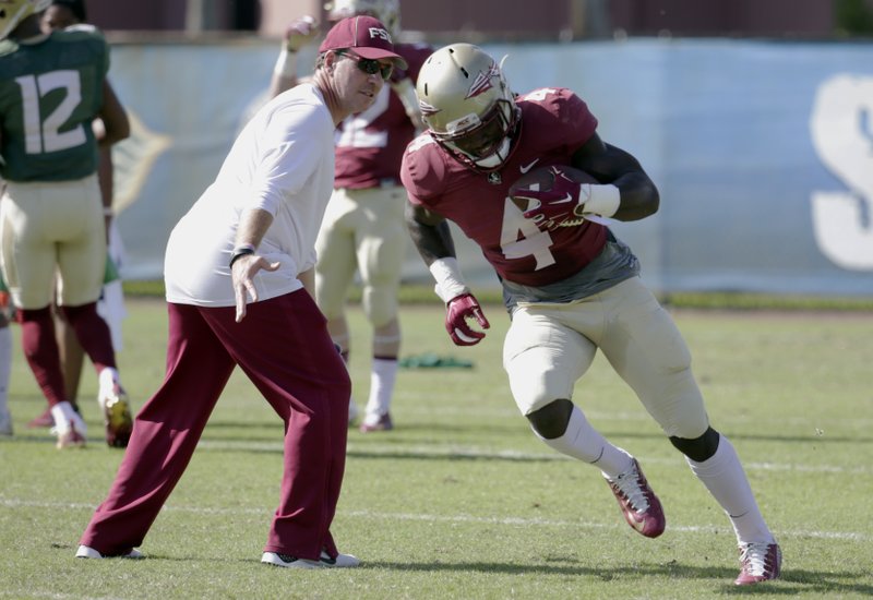 FILE - In this Dec. 27, 2016, file photo, Florida State running back Dalvin Cook (4) runs as head coach Jimbo Fisher looks on during NCAA college football practice in Fort Lauderdale, Fla. The two-a-day football practices that coaches once used to toughen up their teams and cram for the start of the season are going the way of tear-away jerseys and the wishbone formation. (AP Photo/Lynne Sladky, File)