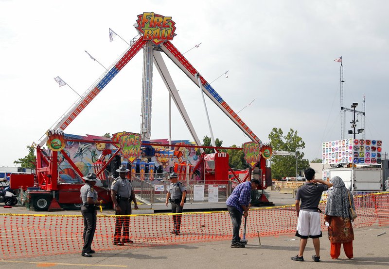 Passers by look at the Fire Ball ride as Ohio State Highway Patrol troopers stand guard at the Ohio State Fair Thursday, July 27, 2017, in Columbus, Ohio. 
