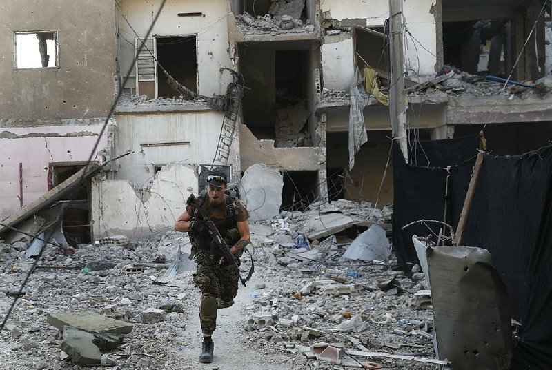 A U.S.-backed Syrian Democratic Forces fighter on Thursday crosses a street on the front line of fighting with the Islamic State in Raqqa, Syria.