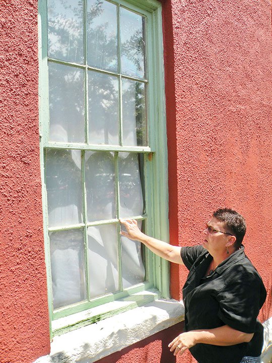 Lynita Langley-Ware of Greenbrier, director of the Faulkner County Museum, discusses the historic windows at the museum that need to be restored. The museum recently received a grant from the Arkansas Historic Preservation Program to complete the project, which also includes replacement of the front door and painting the building.
