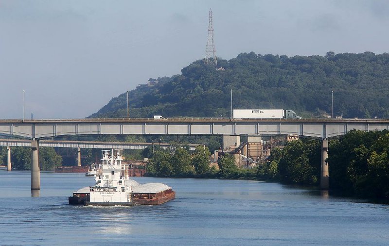 A towboat pushing six barges up the Arkansas River is visible from the Van Buren side.