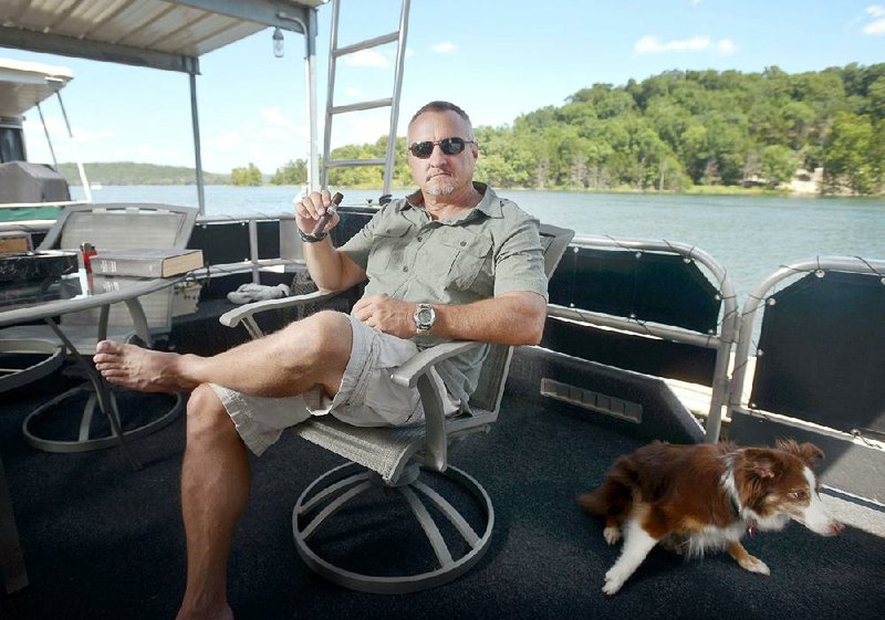 Brian C. Waters poses for a photo Friday, July 21, 2017, in his favorite personal space, the front porch of his house boat docked at Rocky Branch Marina on Beaver Lake near Rogers. 