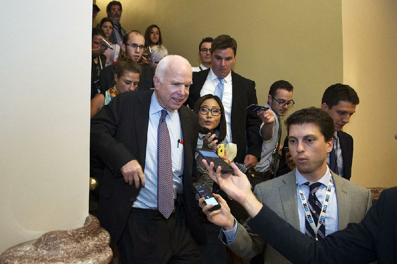 Sen. John McCain, R-Ariz., is pursued by reporters Friday on Capitol Hill after casting a no vote on a measure to repeal parts of the 2010 health care law. 
