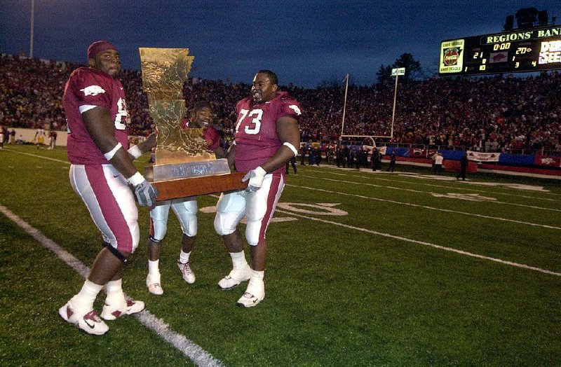 Arkansas’ Jason Peters (left), Shawn Andrews (right) and Fred Talley carry the Golden Boot Trophy off the ÿeld after the Razorbacks’ victory over LSU in 2002.