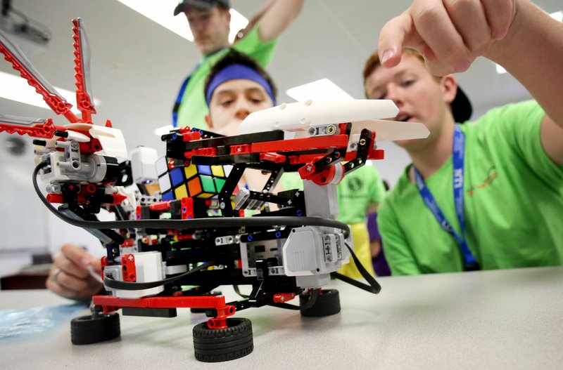 Paul Tribble (from right), 13, Caden McHaney, 13, and Hunter Keen, 17, monitor their Lego Mindstorms computer Friday during the Young Manufacturers Academy at Northwest Technical Institute in Springdale. The computer was able to solve a Rubik’s Cube. NTI’s Business and Industry unit received a $5,000 grant to offer the academy for a second year. Students received lessons in welding, used 3-D printers and toured Kawneer as part of the activities.