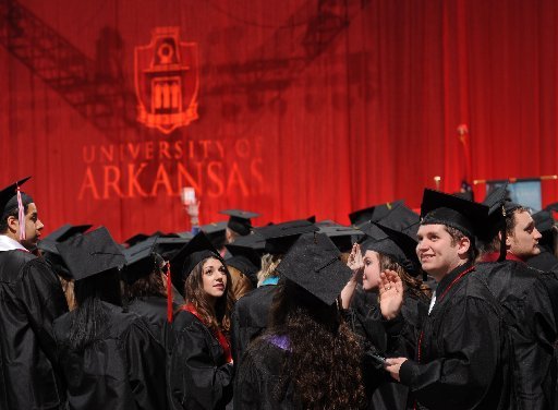 Eli Leslie (right) of Van Buren waves to family Saturday, Dec. 19, 2015, before the start of commencement exercises at the University of Arkansas. Fall commencement returned in 2011 and has grown to about 1,200 students, requiring the move to Bud Walton Arena.