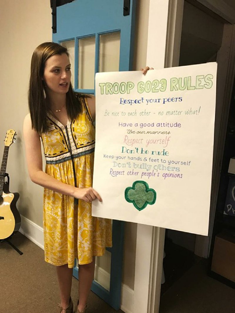 Jordan Camp, the leader of Girl Scout Troop 6023, shows a poster listing the troop’s rules. The Faulkner County troop was the first in its region to serve girls in the juvenile court system. 
