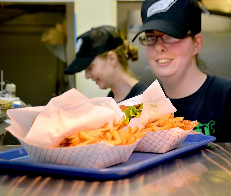 Janelle Jessen/Siloam Sunday Rachael Harris slid an order of hamburgers and fries across the window at Barnett&#8217;s Dairyette last week. The iconic Siloam Springs restaurant recently changed ownership.