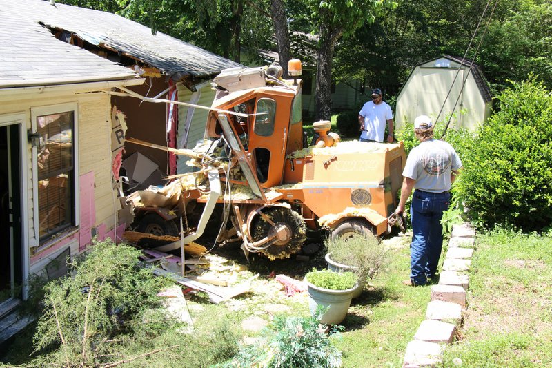 COURTESY BENTON COUNTY Workers remove a street sweeper that crashed into a home near Monte Ne on June 6, pinning a woman and her infant son underneath it. The woman, Teresa Ruiz, remains in a Springÿeld, Mo., hospital with multiple injuries. Her son wasn’t seriously injured.