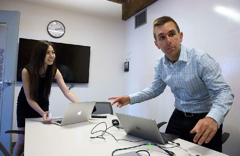 Todd Horton (right) and intern Minjee Kim, of Seoul, South Korea, prepare for a Skype connection in a conference room in Arlington, Mass., earlier this month. At Horton’s human resources software company, KangoGift, four staff members work together in Boston and six are remote, scattered in Europe and India.