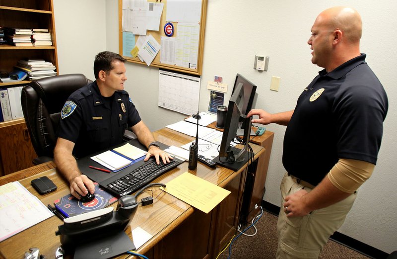 Lt. Tad Scott, with the Fayetteville Police Department, pulls up an electronic warrant form July 20 as he discusses the process with Cpl. Dallas Brashears at the department. Judges in Washington County are now signing search warrants electronically and swearing in and taking police statements over the phone.