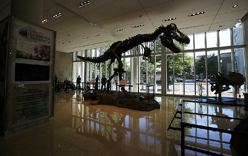 A replica of a Tyrannosaurus rex is displayed in the lobby of Discovery Communications headquarters in Silver Spring, Md., on Monday. Discovery Communications announced Monday that it has agreed to buy Scripps Networks Interactive in a $14.6 billion deal.