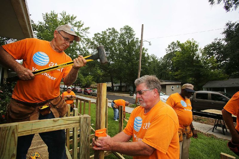 Greg Kern (left) uses a sledgehammer to drive a stake into place while J.D. Little (center) holds it level while building a wheelchair ramp at a home on Marlborough Street in Little Rock on Wednesday. 