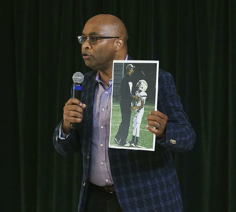 Fitz Hill, a member of the Arkansas Board of Education, holds a photo of himself coaching his son Thursday during a news conference to announce the start of a sixth-grade football program in the Little Rock School District and the formation of a Little Rock School District Athletic Foundation.