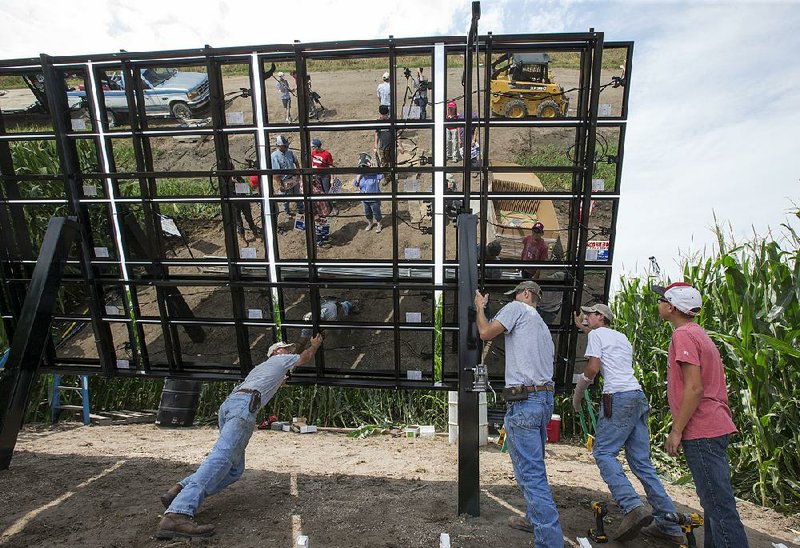 Volunteers and installers push a solar panel array into place on farmer Jim Carlson’s cornfield near Silver Creek, Neb., on Saturday. The proposed Keystone XL pipeline route takes it across Carlson’s farm, and the panel is a form of protest. 