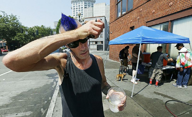 Mike Cook, who said he had spent most of the day walking outside, takes a break for ice water being given away outside Union Gospel Mission in Seattle.