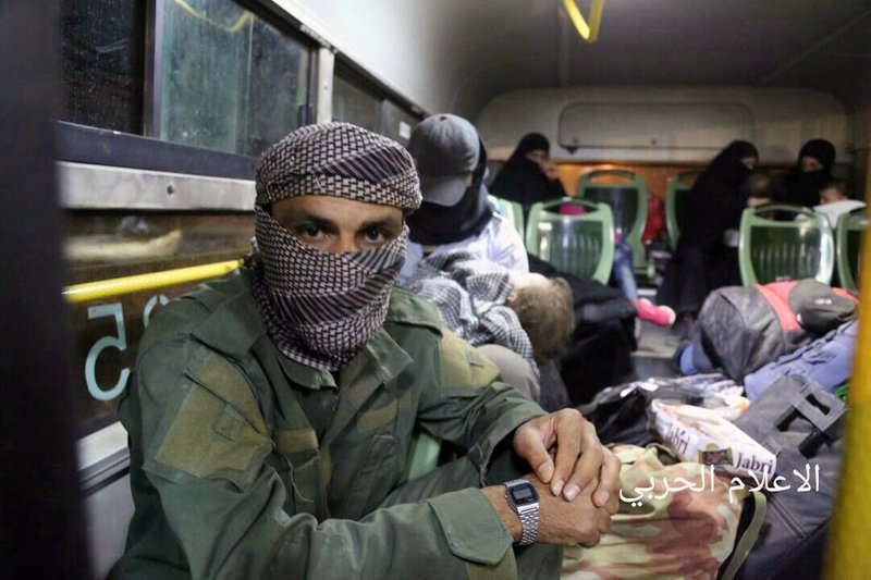 This Thursday, Aug. 3, 2017 photo released by the government-controlled Syrian Central Military Media, shows al-Qaida-linked militants seated in a bus with their families, after being evacuated from the town of Arsal, near the Syrian border, in northeast Lebanon. 