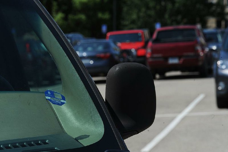 Cars sit Friday in Lot 71 on the University of Arkansas campus in Fayetteville. A planned change to a new system of parking enforcement has been delayed, forcing the university to continue issuing permit decals for the coming academic year.