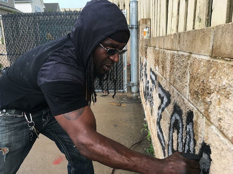 Activist Tyree Colion earlier this week spray paints “No Shoot Zone” on a wall behind a convenience store near the spot where a 13-year-old girl was fatally shot in Baltimore County, Md. Police arrested him for destruction of private property.  