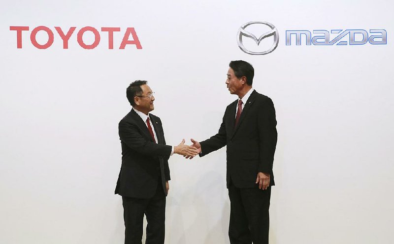 Toyota Motor Corp. President Akio Toyoda (left) and Mazda Motor Corp. President Masamichi Kogai end a news conference Friday in Tokyo where Toyoda said automakers now have to compete with “totally new players like Google and Amazon.