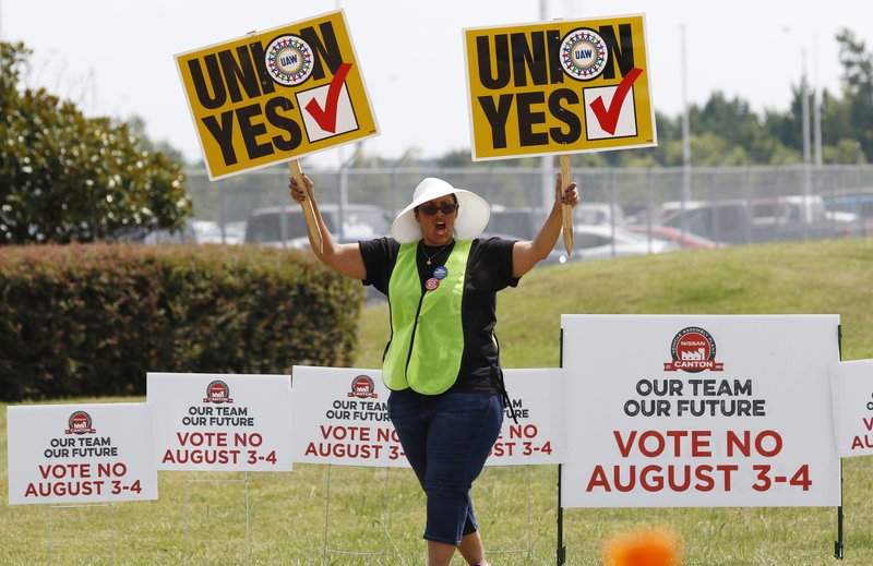 A UAW supporter sings as she tries to beat the hot sun outside an employee vehicle entrance at the Nissan vehicle assembly plant in Canton, Miss., Friday, Aug. 4, 2017. Union members set up informational lines outside employee entrances at the plant and greeted all shifts of workers arriving and leaving, reminding workers to vote for the union. The vote for union representation of line workers concludes Friday evening. (AP Photo/Rogelio V. Solis)
