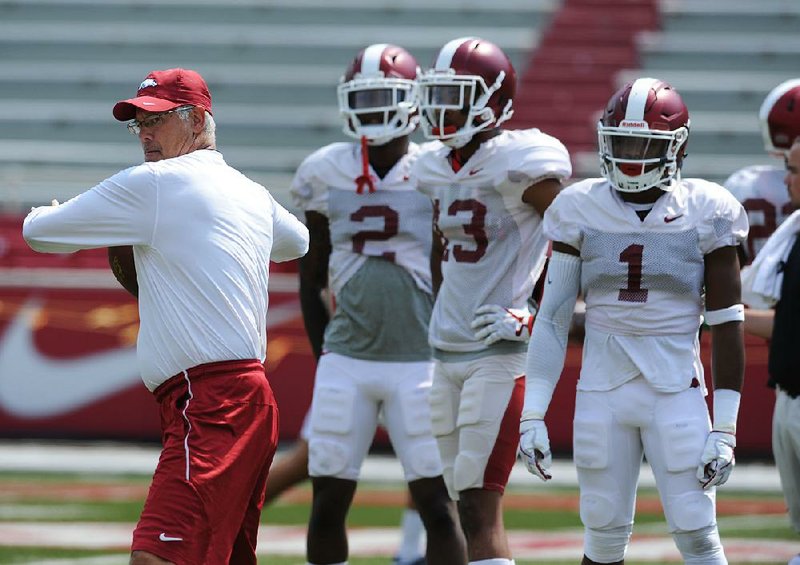 Arkansas defensive coordinator Paul Rhoads throws to members of the secondary Aug. 5 prior to the start of a scrimmage in Razorback Stadium in Fayetteville.
