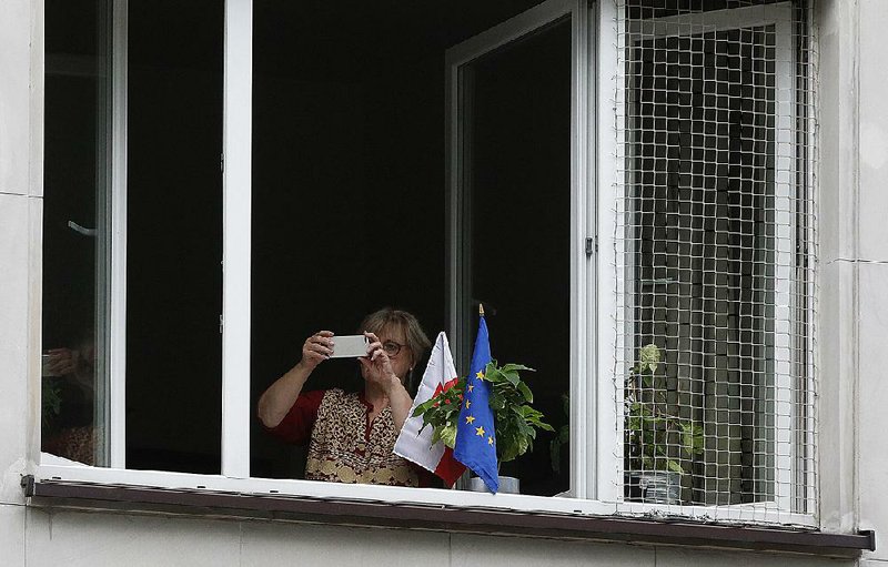 A Polish woman displays a European Union flag in her window during an EU street protest in Warsaw.