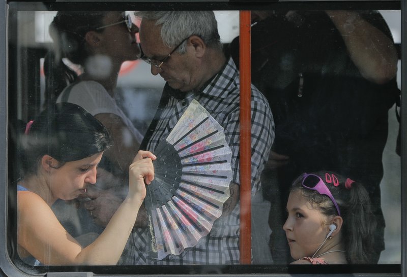A woman uses a fan to cool herself and a child wile ridding on a tram in Bucharest, Romania, Friday, Aug. 4, 2017. Romanian meteorologists issued an extreme temperatures warning, with 42 Celsius (107.6 F) forecast for parts of western Romania and placing 12 counties under a &quot;red code&quot; heat alert for the next two days. 