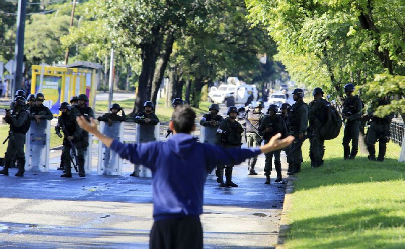 A man confronts Venezuelan national guardsmen Sunday outside the Paramacay military base in the city of Valencia near Caracas, where assailants reportedly were repelled after a pre-dawn attack.