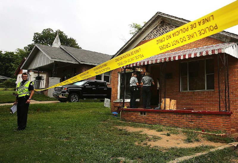 Little Rock police officers and crime scene unit members search a house on Howard Street after a homicide on Aug. 6.